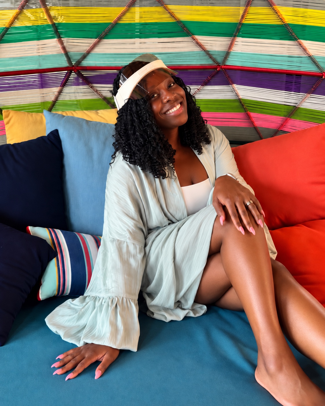 Denise Taylor sitting in a colorful lounge chair, smiling in a calm and bright setting.