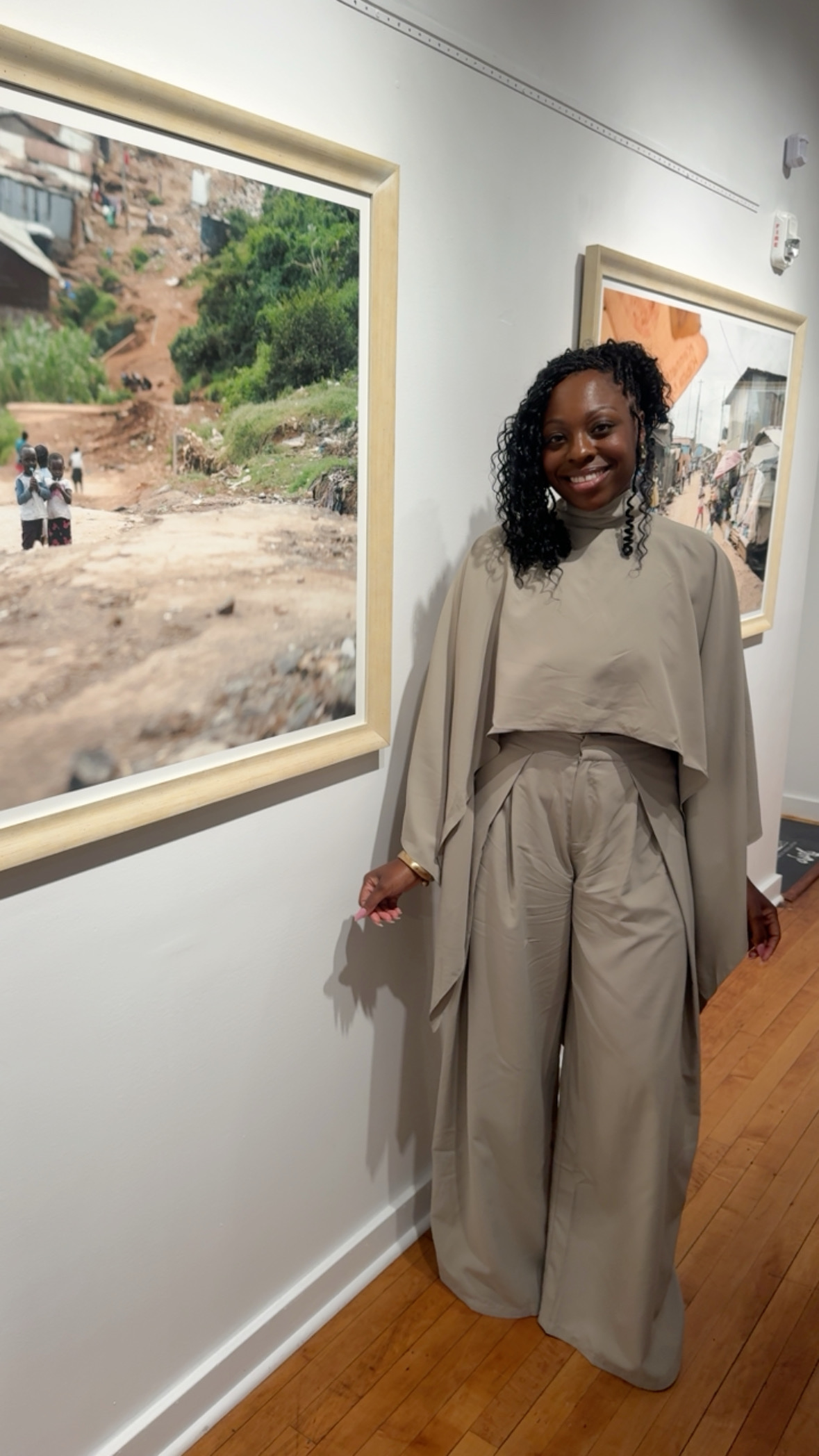 Denise T. Taylor standing in an art gallery wearing a warm neutral-toned outfit